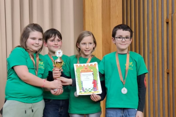 Four children in green shirts holding a trophy.